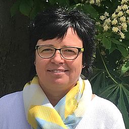 Die Leitung Frau Schreier aufgenommen im Garten des AWO Hortes. Im Hintergrund befindet sich ein Kastanienbaum